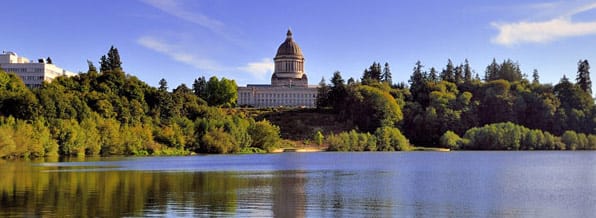 The dome of the Washington state capitol in Olympia, reflected in water, and surrounded by trees