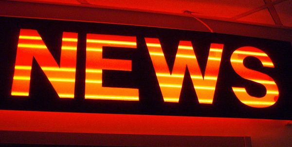 An orange, red, and yellow neon sign with the word "news"